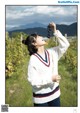 A woman holding a bunch of grapes in a vineyard.