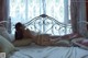 A woman laying on a bed in a white lingerie.
