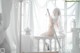 A woman in a white lingerie sitting on a white chair.