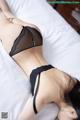 A woman laying on a bed in a black lingerie.