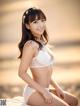 A woman in a white lingerie sitting on a beach.