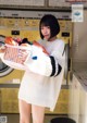 A woman holding a basket full of clothes in a laundry room.